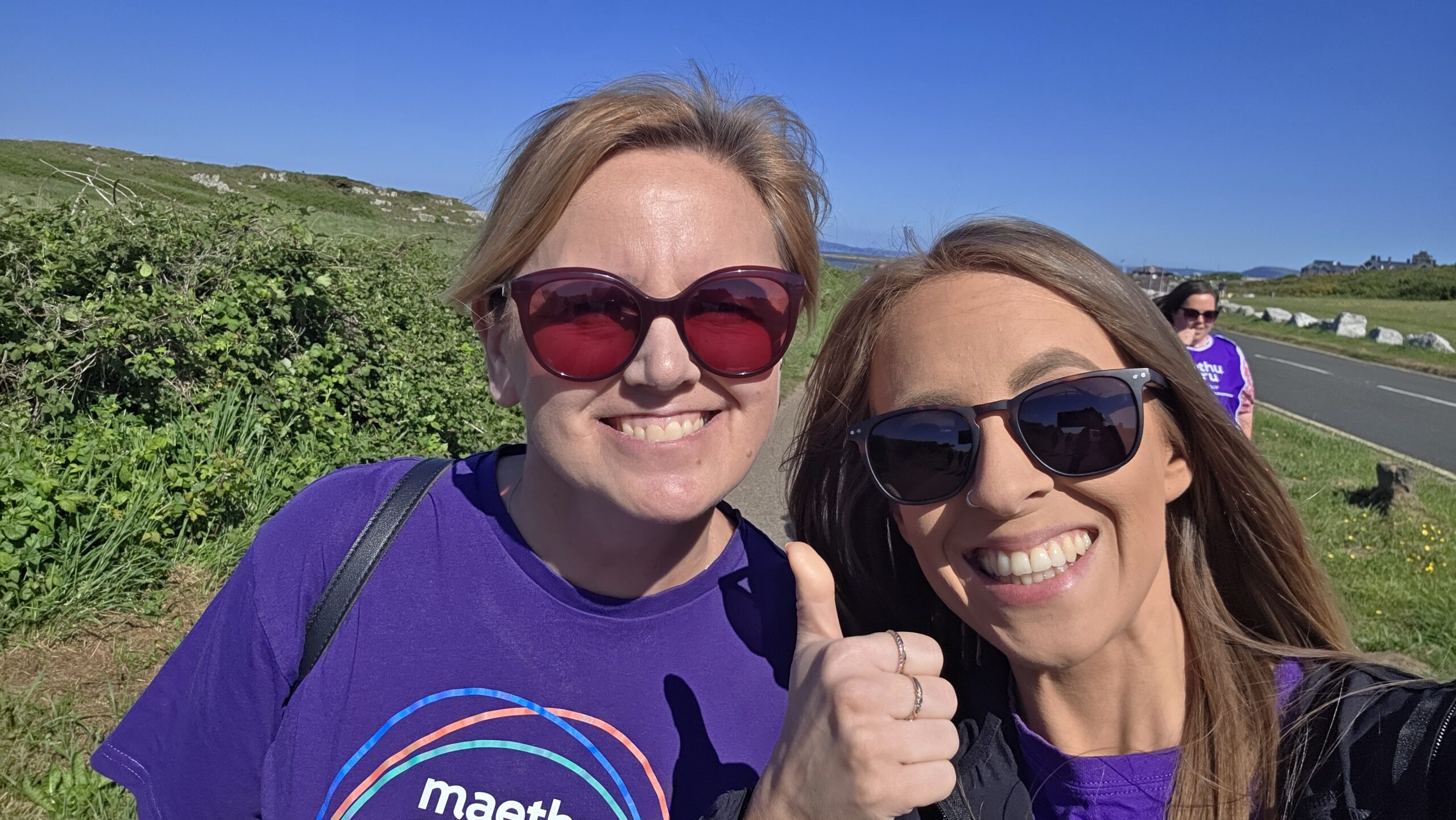 two women outside smiling with one thumbs up
